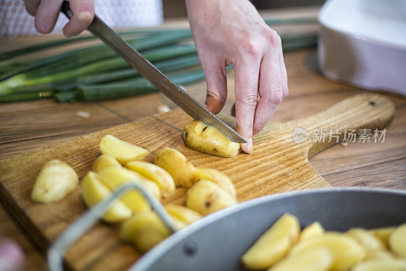 女性的手在木板上切土豆。