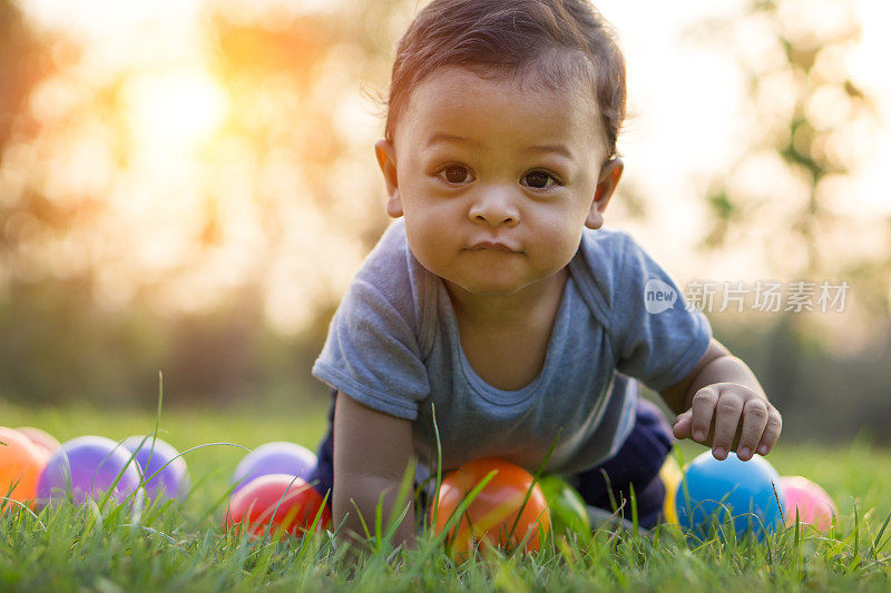 可爱的亚洲婴儿爬在草地和彩色球