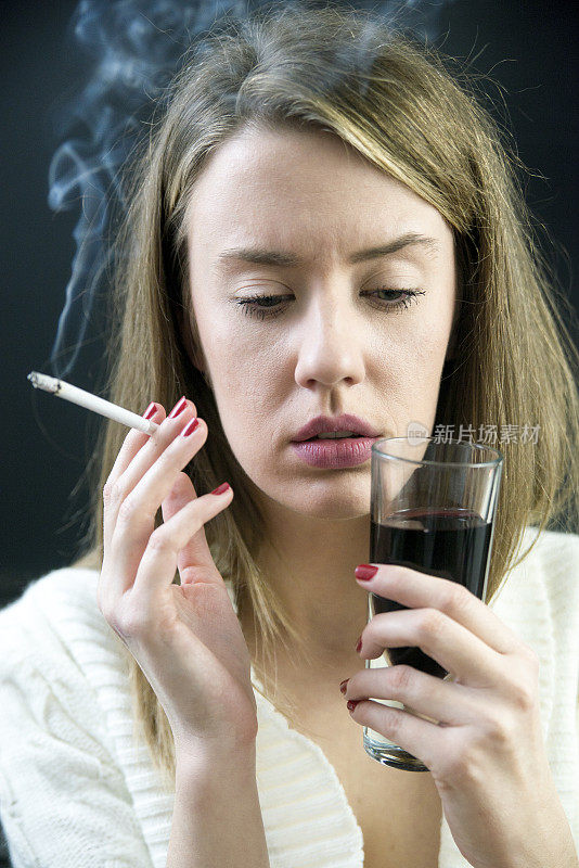 可悲的女人，一边抽烟，一边拿着葡萄酒杯