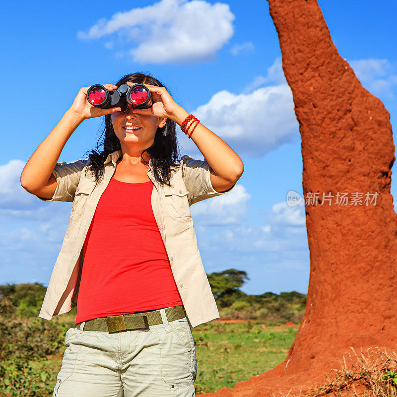 一名年轻女子在狩猎旅行中用双筒望远镜看东西