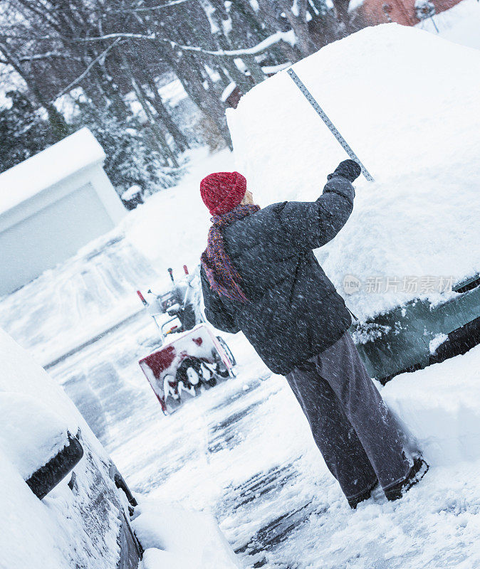 冬天女人测量汽车上的厚雪