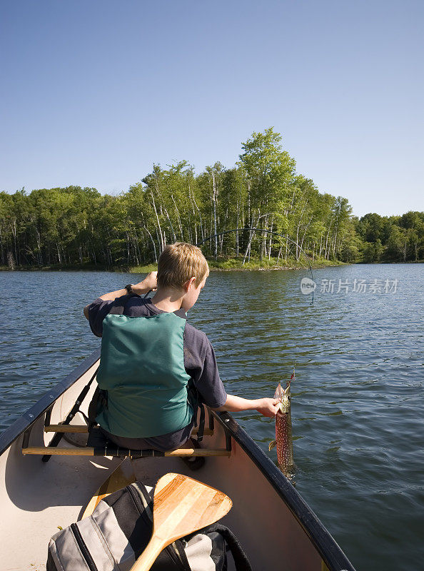 男孩在独木舟上钓鱼