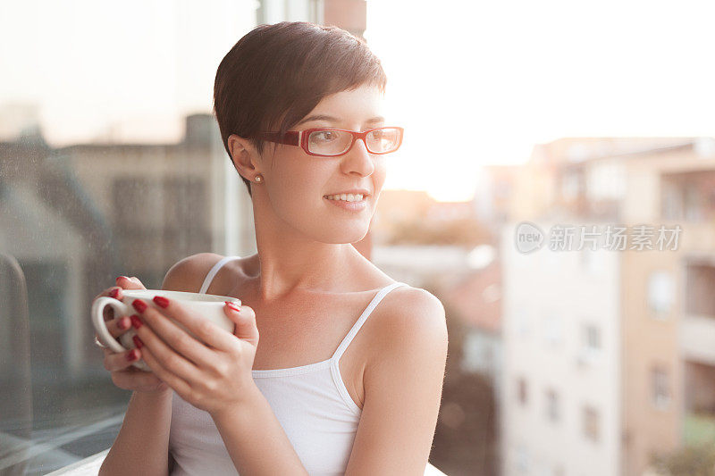 在阳台上喝咖啡的女人