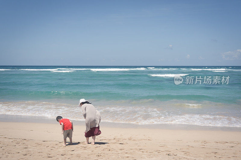 母亲和儿子在海滩上寻找