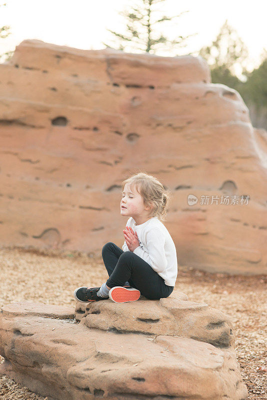 一个小女孩在自然的操场上休息，她自己做了一个小小的祈祷