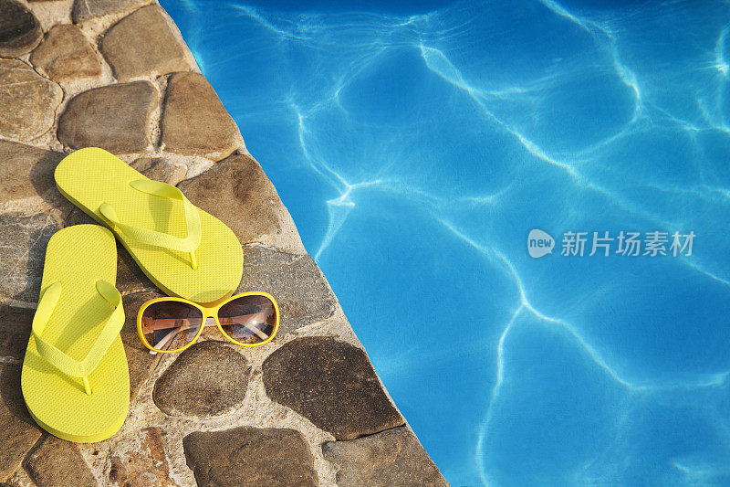 游泳池边有黄色拖鞋和太阳镜