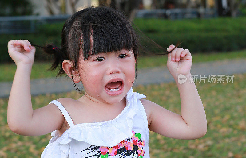 特写可爱的小女孩在公园里哭泣。