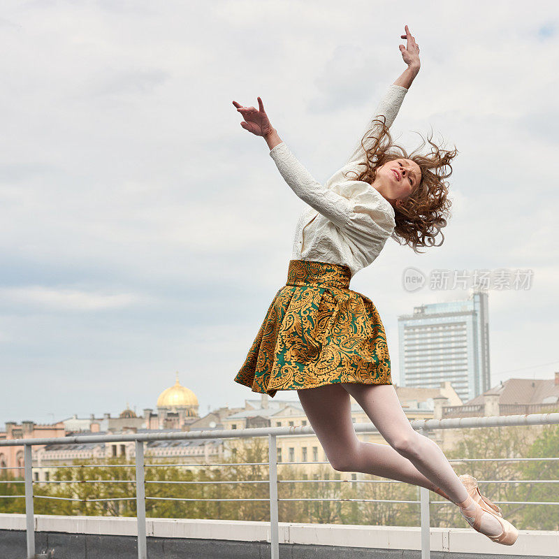 年轻的白人时尚芭蕾舞演员在屋顶上跳跃