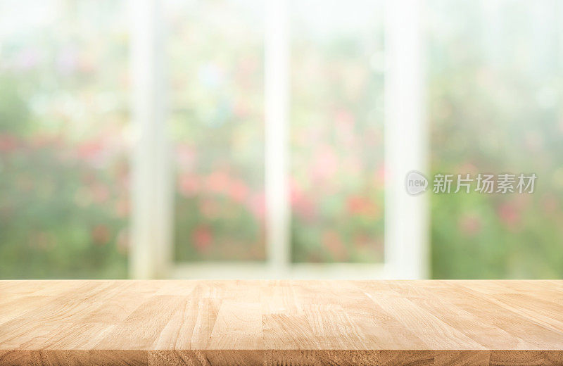 木质桌面上模糊的窗户与花园的花朵