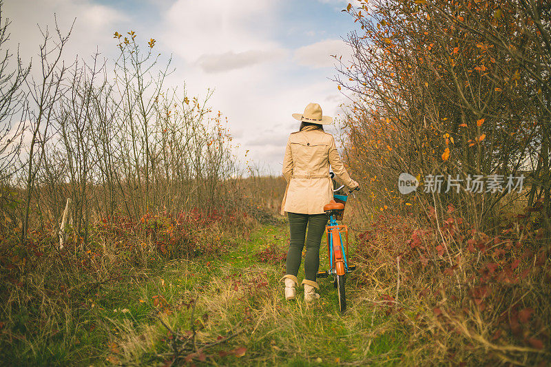 女孩骑着自行车穿过秋天的森林
