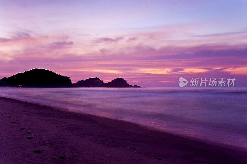 太阳在海滩上冉冉升起，天空五彩缤纷