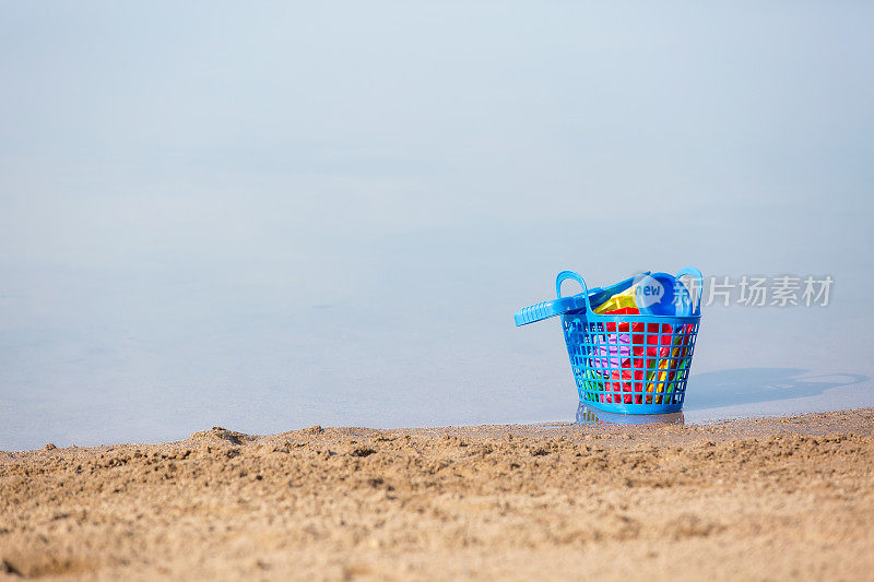 在非常平静的水中放置沙滩玩具的篮子
