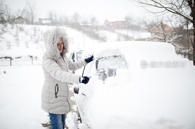 女人在清理被雪覆盖的汽车