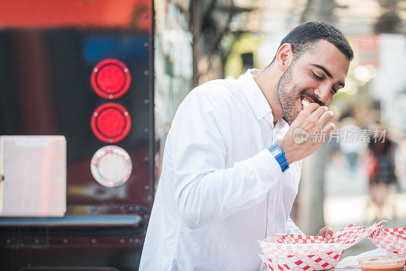 一名亚美尼亚男子在餐车旁咬三明治