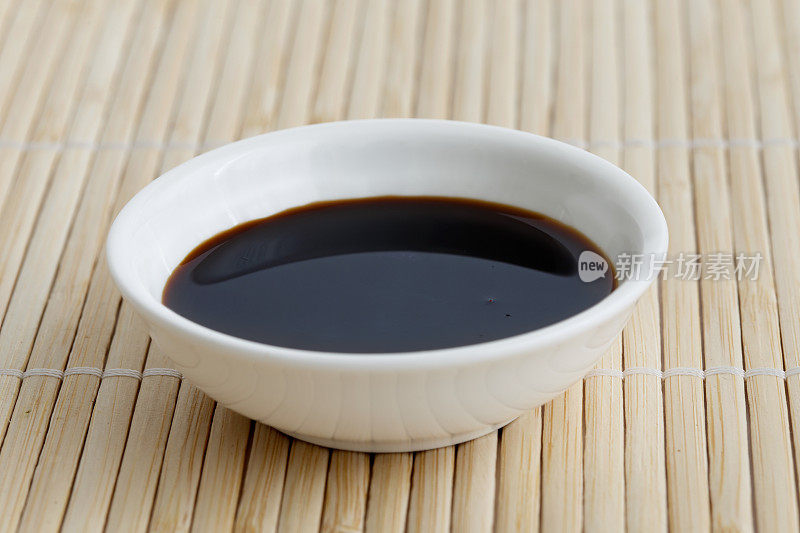 酱油在白色陶瓷碗孤立在竹席上。