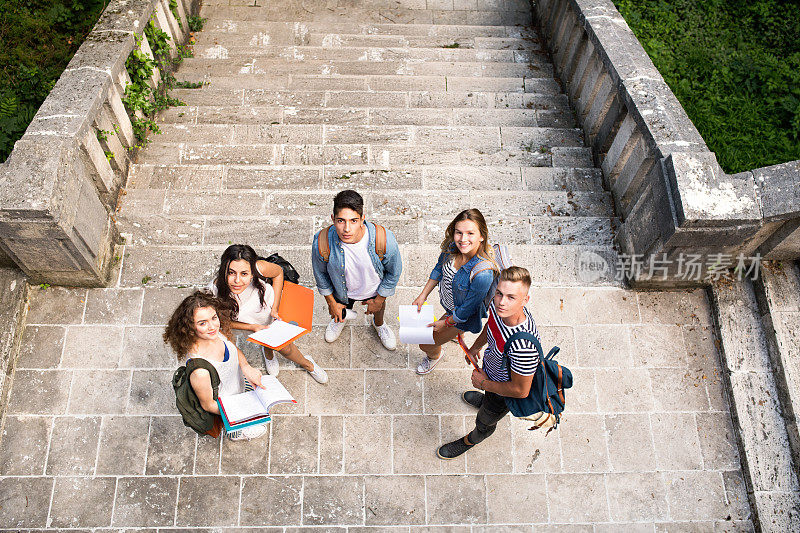 十几岁的学生站在大学前的石阶前。