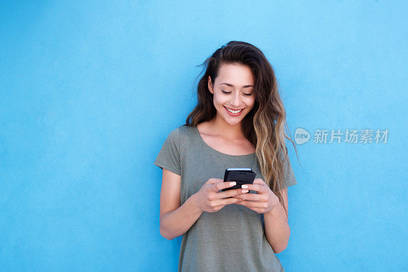年轻微笑的女人用手机在蓝色的背景