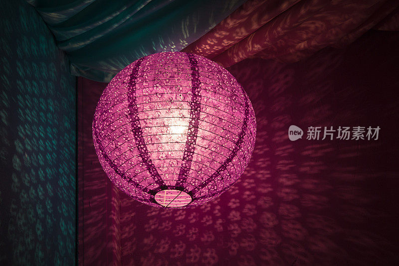 粉红色的中国纸灯笼，以粉红色和蓝色的纺织品为背景