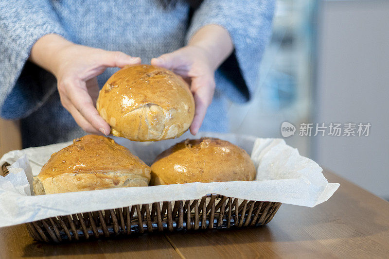 用手把新鲜出炉的小圆面包放进篮子里