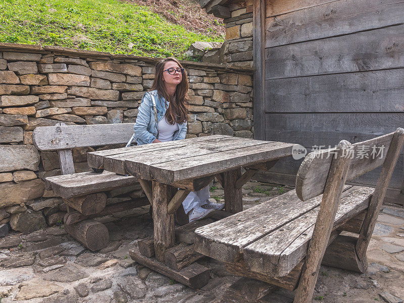 年轻女子，一名游客，坐在户外的旧木凳和桌子上休息