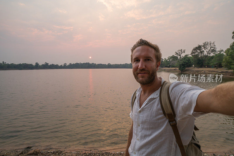 在柬埔寨旅行的年轻人在湖边用手机自拍。人们旅游发现亚洲的概念。