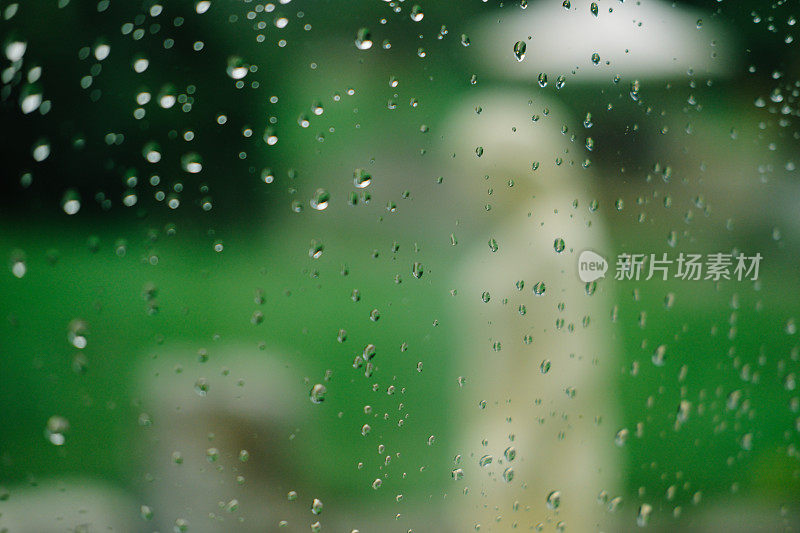 雨滴落在绿色背景的窗户上