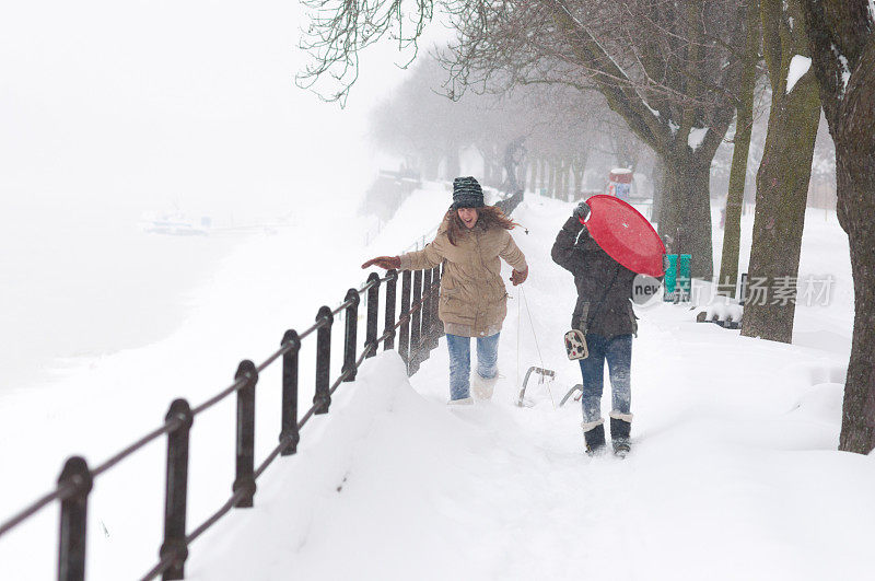 两个十几岁的女孩在暴风雪中玩雪橇