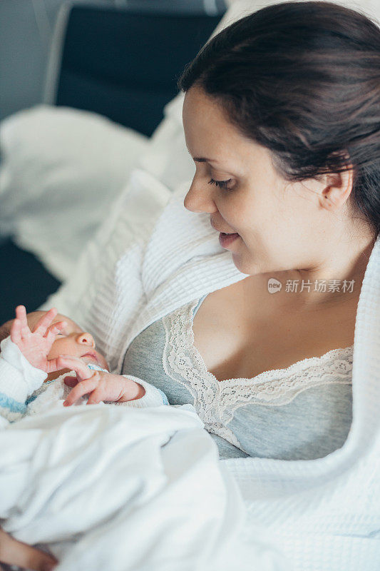 母亲抱着刚出生的婴儿躺在病床上