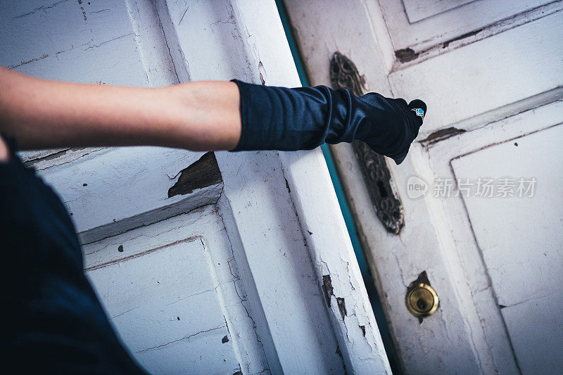 女性手戴手套打开旧的和废弃的门。