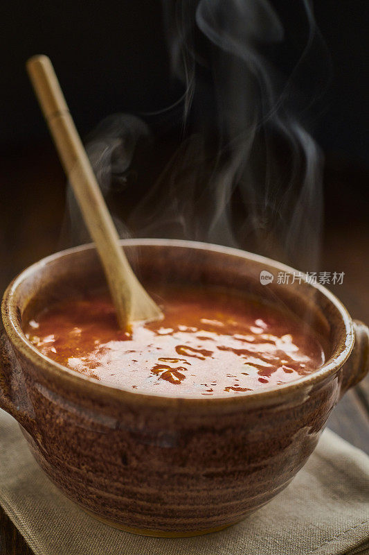 一碗辣鸡肉，米饭和辣香肠汤放在一个古老的木头桌面上。