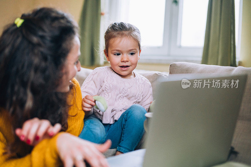 母亲和女儿在沙发上使用笔记本电脑