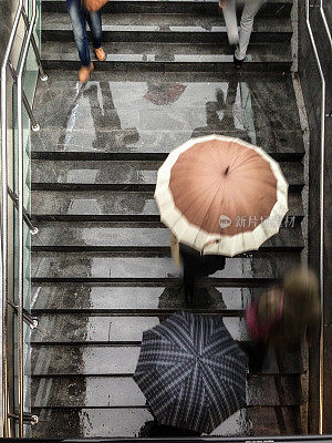 地铁楼梯上撑着雨伞的人们的鸟瞰图