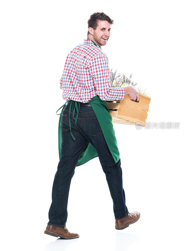 快乐的男性花商拿着一个篮子的植物和行走
