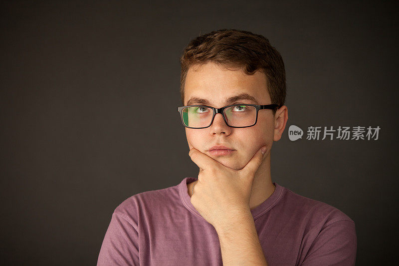 一名18岁男子的摄影肖像画，戴着眼镜，身穿紫色t恤，背景是黑色