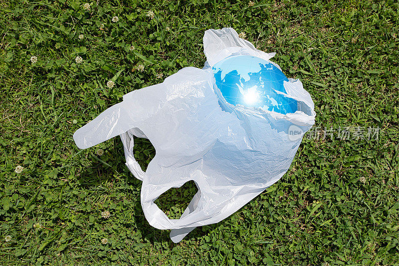 废弃的塑料购物袋。里面是一个绘有世界地图的弹力球。环境污染的微塑料图像。