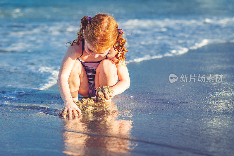 漂亮的红发小女孩在海滩上玩耍