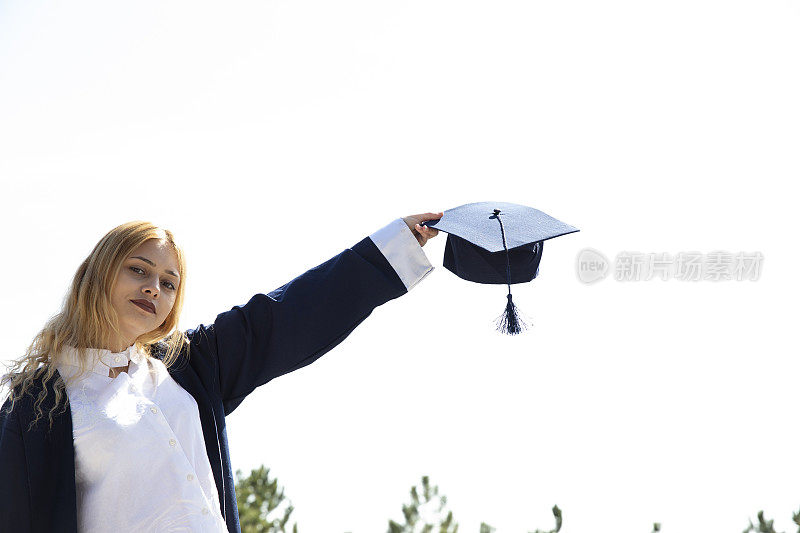 教育的主题。漂亮的女生向空中抛毕业帽庆祝