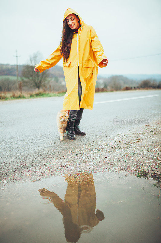 快乐的女孩和猫在大自然的雨