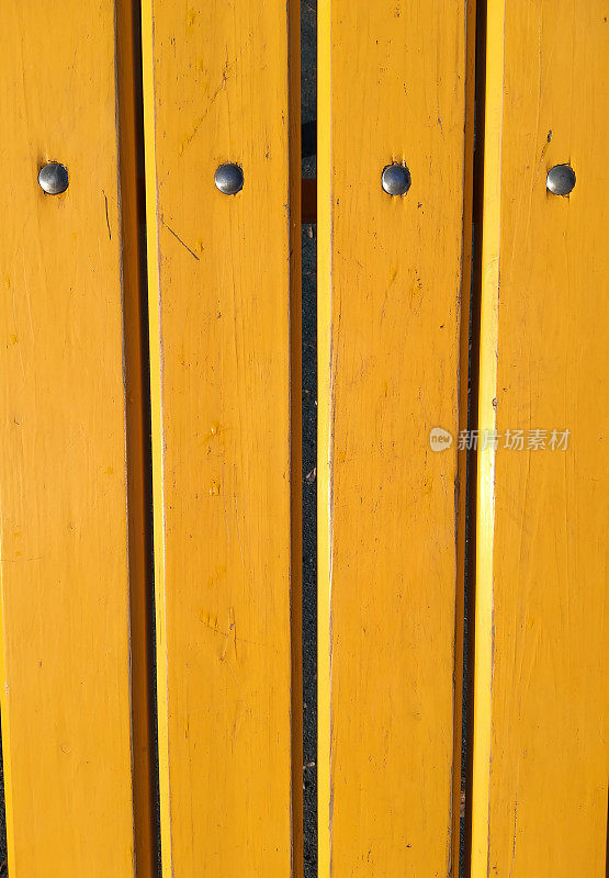 木板涂上黄色油漆，木栅栏带金属铆钉，墙壁，垂直背景