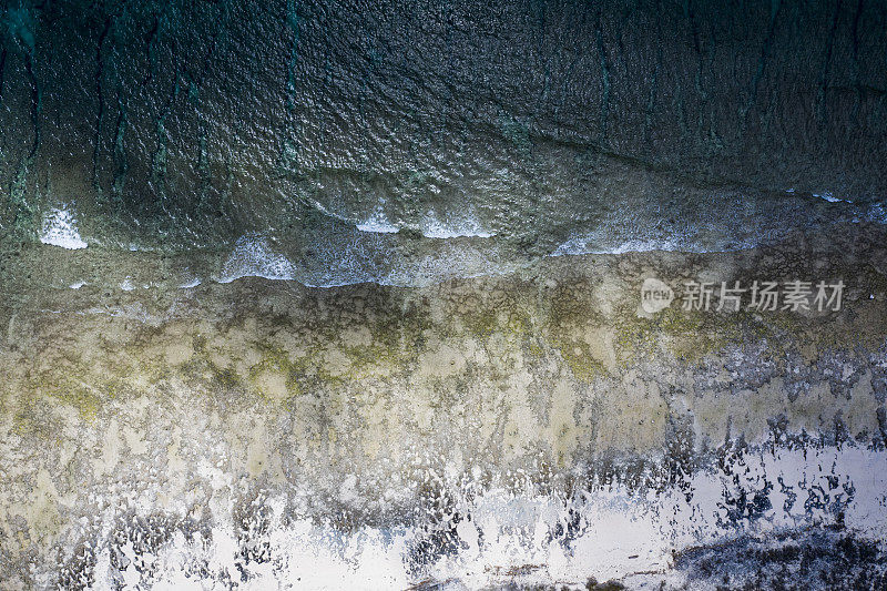 无人机拍摄的岩石海滩，海浪溅起水花