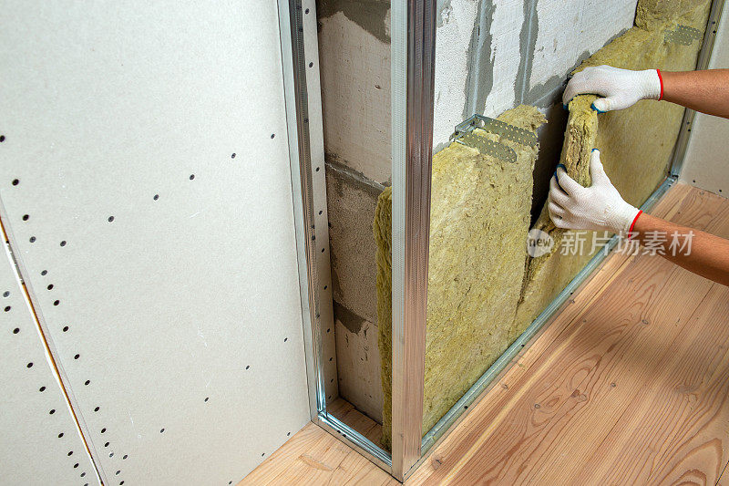 工人用矿物岩棉隔热隔离房间墙壁。