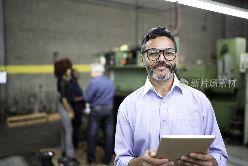 一个商人在工厂的生产线上使用数字平板电脑的肖像
