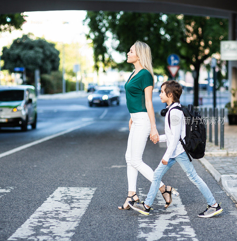 一个背着背包的小学生和妈妈正在过马路