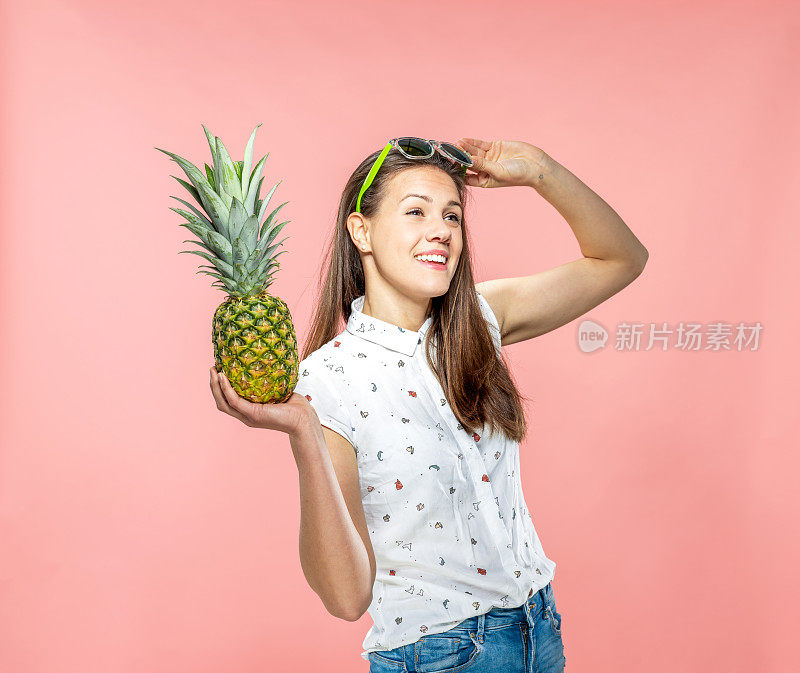 快乐年轻女子拿菠萝在珊瑚背景-存货照片