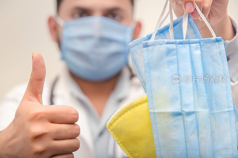 医生身穿白大褂，手持白手套，手持医用一次性纺织品口罩。流行病毒爆发概念