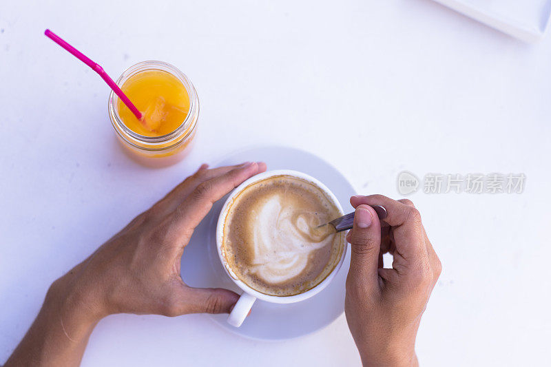 女人手里拿着一杯咖啡，除了橙汁。健康的早餐。俯视图