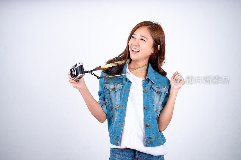 美丽的亚洲女人很高兴拿着相机在一个白色的工作室背景。
