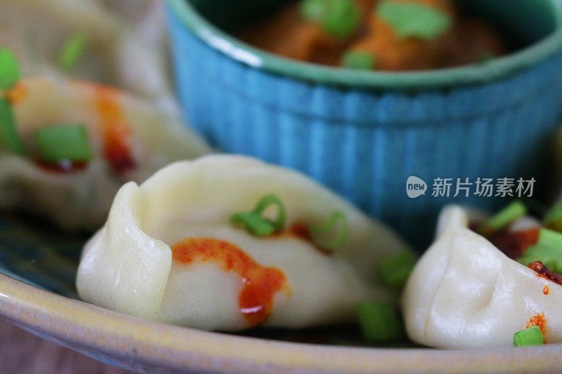 这是蒸过的馍馍(南亚饺子)，用白面粉和水面团填满鸡肉和什锦蔬菜，淋上辣椒油，放在盘子里，周围是用橙子辣酱做的小模子