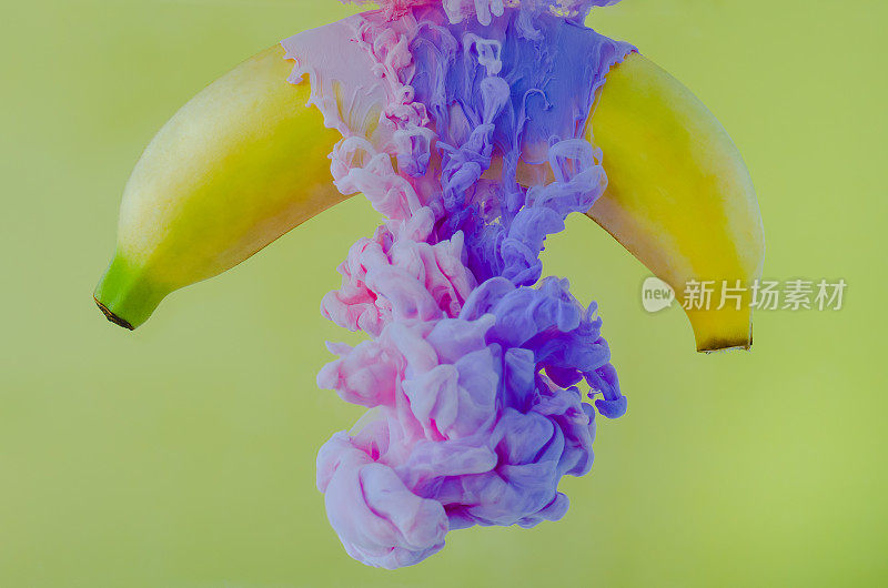香蕉水果的部分焦点溶解粉红和紫色的海报颜色在水中。