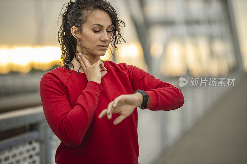 年轻的运动女性在智能手表上检查心率